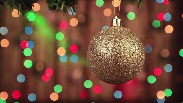 Close-up of golden Christmas balls on a background of twinkling lights. New Year's multi-colored garlands in defocus. Holiday card with bokeh. Abstract background for captions and text. UHD 4K.
