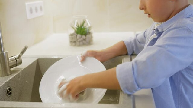 Independent child washing up, using foamy dishwashing detergent, kitchen chores