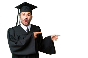 Young university graduate man over isolated chroma key background surprised and pointing side