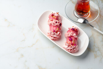 Eclair dessert with pink icing on white table