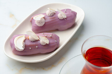 Two eclair cakes with violet frosting on white plate