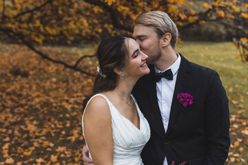 Groom cheek kissing his bride. Outdoor wedding photoshoot. High quality photo