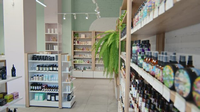 Tilt down of tall and long display with many shelves with rows of various cosmetic products in large supermarket selling beautycare stuff