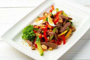 Beef salad with vegetables served on white plate
