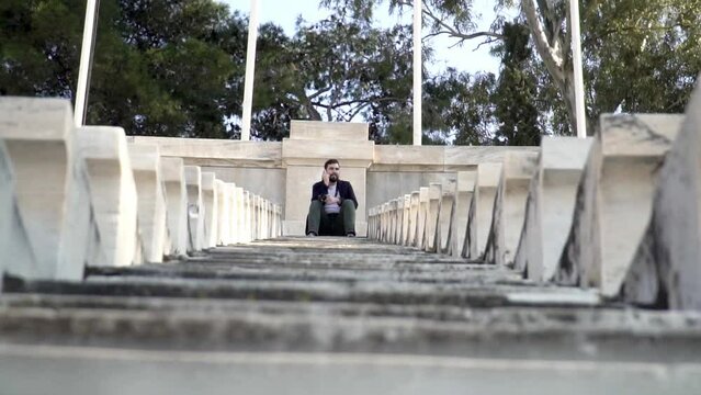 Man talking on cell phone while sitting on stairs at the top of Panathenaic stadium in Athens Greece