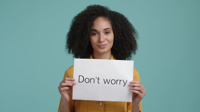 Cute, brunette-haired woman with a positive facial expression. Young girl holding a white card with optimistic expression. High quality 4k footage