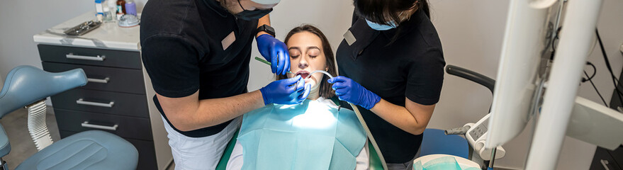 woman smiles during dental treatment at the dentist by a man and his female assistant.