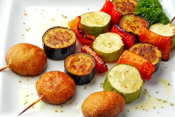 Grill vegetable kebabs on skewers in white plate