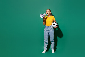 Fototapeta na wymiar Full body fun young woman fan wear yellow t-shirt cheer up support football sport team hold soccer ball watch tv live stream hold scream in megaphone announces news isolated on dark green background.