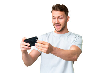 Young handsome caucasian man over isolated chroma key background playing with the mobile phone