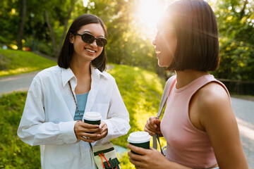 Two young beautiful smiling asian girls in glasses with coffee