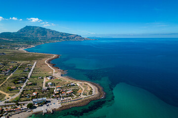 Aerial view of the mountains and the Mediterranean coast. Sunny cloudless day in Cornino, Sicily. In the background, buildings and turquoise water