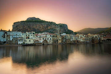 Fototapeta na wymiar Sunrise behind the mountain. View of the old town of Cefalu, Mediterranean coast, Sicily, Italy.