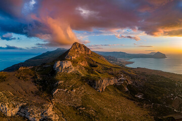 Obraz premium Photo from the drone on the panorama of the Mediterranean coast. View of Monte Monaco and Monte Cofano in the distance. The colorful sky covers the top of the mountain. golden hour. Sicily. Italy
