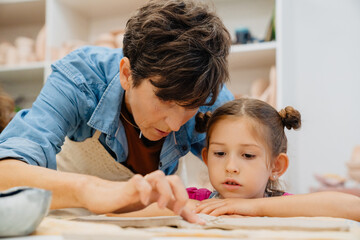 Obraz premium Mature woman working with girl at ceramics class