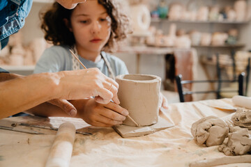 Woman teaching boy to make clay crafts at workshop