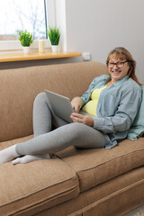 Obraz premium Technology, old age and people concept - happy senior woman in glasses with laptop computer and glass of wine at home