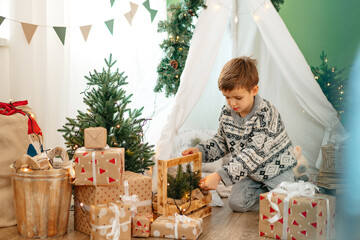 A little boy lying in a children's wigwam decorated for Christmas