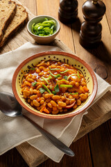 Beans with sausage and tomato sauce. Beans stew, homemade rustic english food. Rustic wooden background.