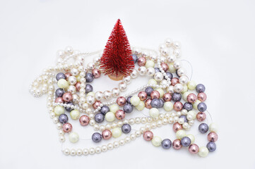 red artificial Christmas tree surrounded by colorful festive garlands on white background. isolated