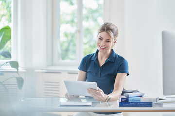 Happy female doctor using digital tablet PC at desk