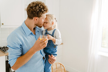 Young white father holding his daughter while drinking tea together - obrazy, fototapety, plakaty