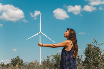 Young woman standing in front of wind turbine
