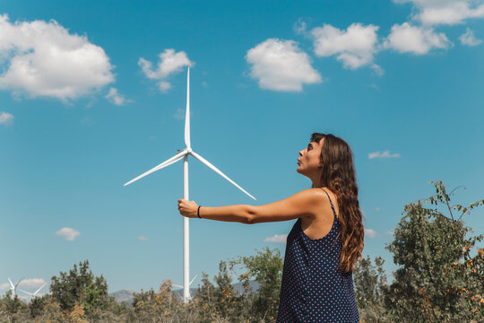 Young woman standing in front of wind turbine