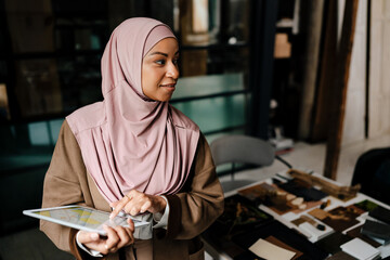 Arabian woman working on tablet while standing in modern office