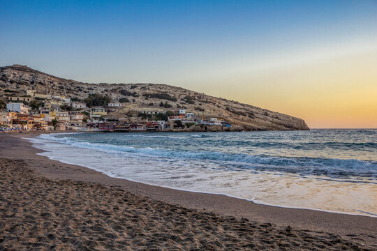 Greece, Crete, Matala, Matala Beach at dusk with village in background