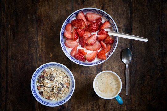 Tray with mug of coffee, muesli and yogurt with strawberries