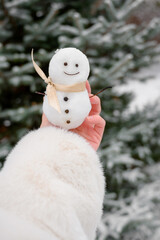 A small snowman in female hands. Cute snowman. winter photo