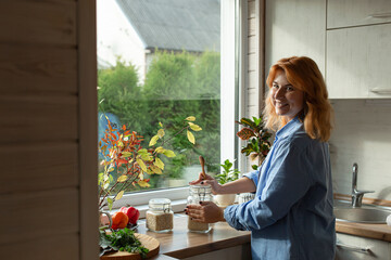 Smiling woman standing in kitchen at the window