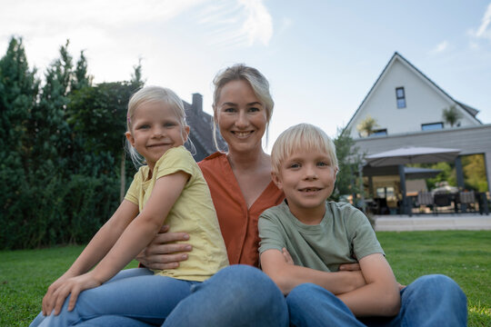 Smiling mother with son and daughter in back yard