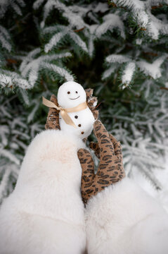 Close-up Of Female Hands Holding A Small Snowman With A Ribbon.Christmas Mood In Winter Day Outdoor