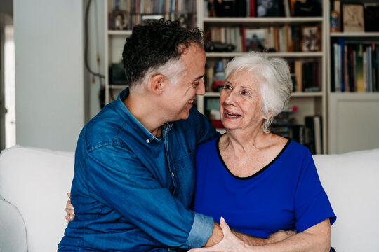 Happy son embracing mother on sofa in living room