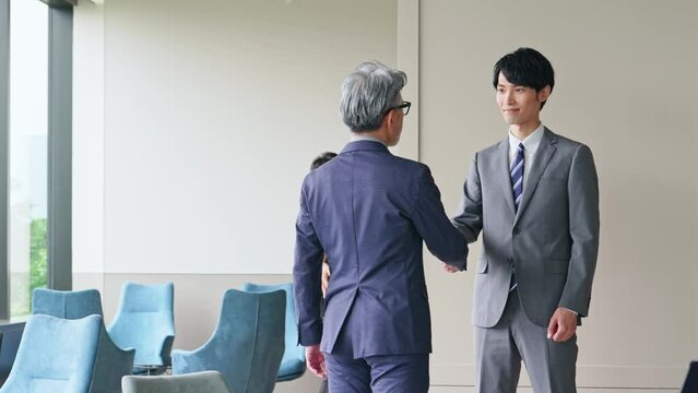 若いビジネスマンと握手するエグゼクティブ男性