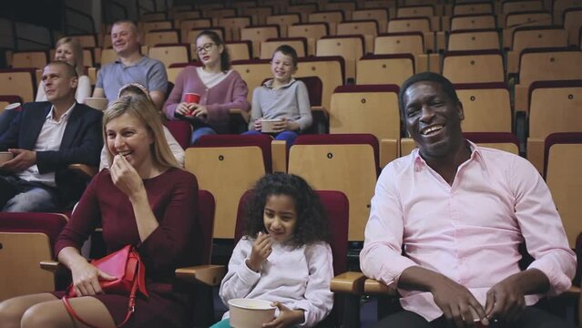  Family with child eating popcorn and watching a movie in the cinema