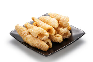 fried pork rinds on a black plate isolated on white background