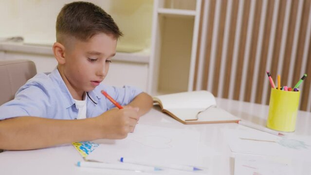 Cute boy drawing read heart with pencil, preparing valentine card for girlfriend
