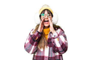 Young caucasian woman wearing winter muffs over isolated chroma key background shouting and...