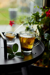 Glass cup of hot black tea lemon on dark background  with steam near window, cozy warm, relaxing.
