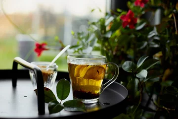 Foto op Plexiglas Glass cup of hot black tea lemon on dark background  with steam near window, cozy warm, relaxing. © bondarillia