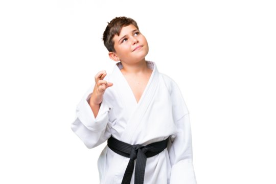 Little caucasian kid doing karate over isolated chroma key background with fingers crossing and wishing the best - Powered by Adobe