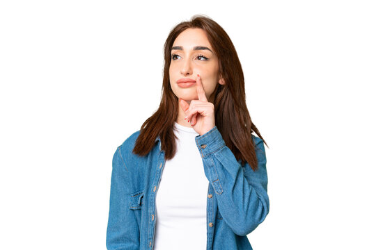 Young caucasian woman over isolated chroma key background having doubts while looking up