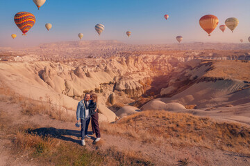 Naklejka premium Cappadocia Turkey travel, happy couple man and woman watching sunrise with hot air balloons in Goreme trip