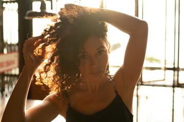 Portrait of a curly woman sitting in backlit