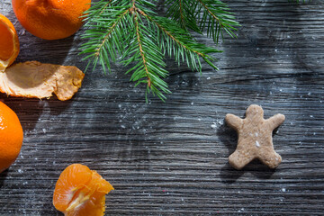 Tangerines, gingerbread and cookies on a wooden table, sprinkled with white flour in the form of snow.