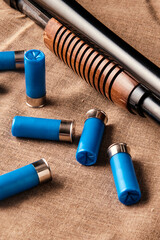 12-gauge shotgun shells scattered on linen against a mahogany pump action shotgun forearm