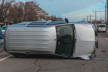 A broken car lies on its side on a city avenue after an accident. Dangerous situation. Traffic...